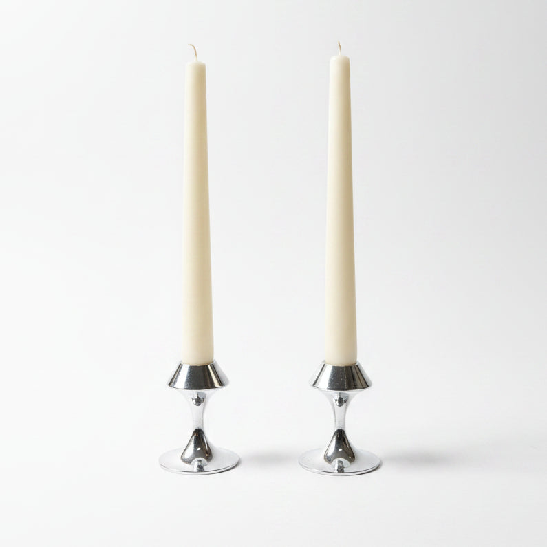 Two white taper candles in polished Lenox silver metal candlesticks.