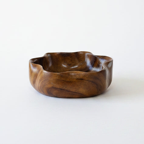 A small, wavy-edged vintage hand-carved wooden bowl with a glossy finish.