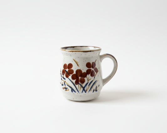 Small ceramic mug with floral design on a wooden surface