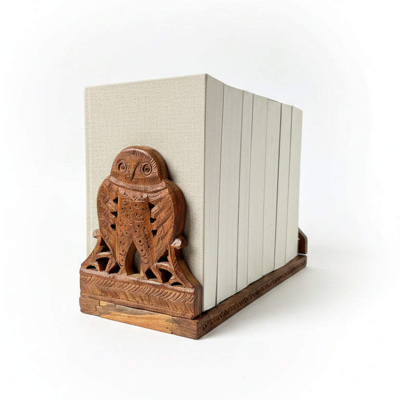 A vintage carved wooden owl extendable bookend set with linen books.
